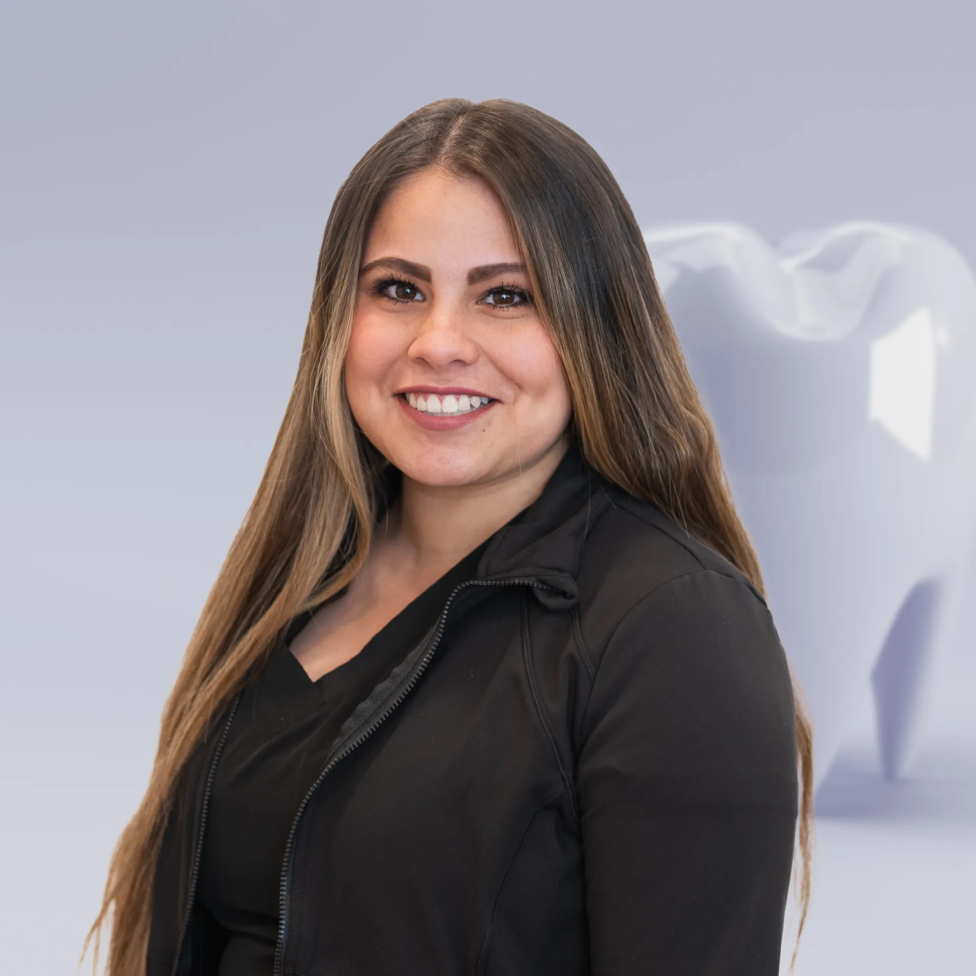 A woman with long hair standing in front of a white sculpture.