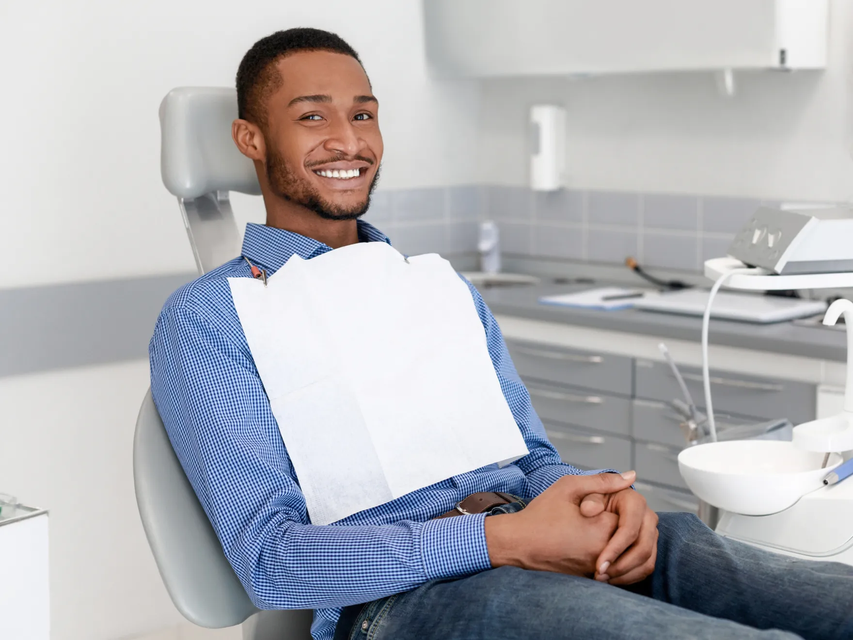 A man sitting in a dentist chair holding a paper bag.