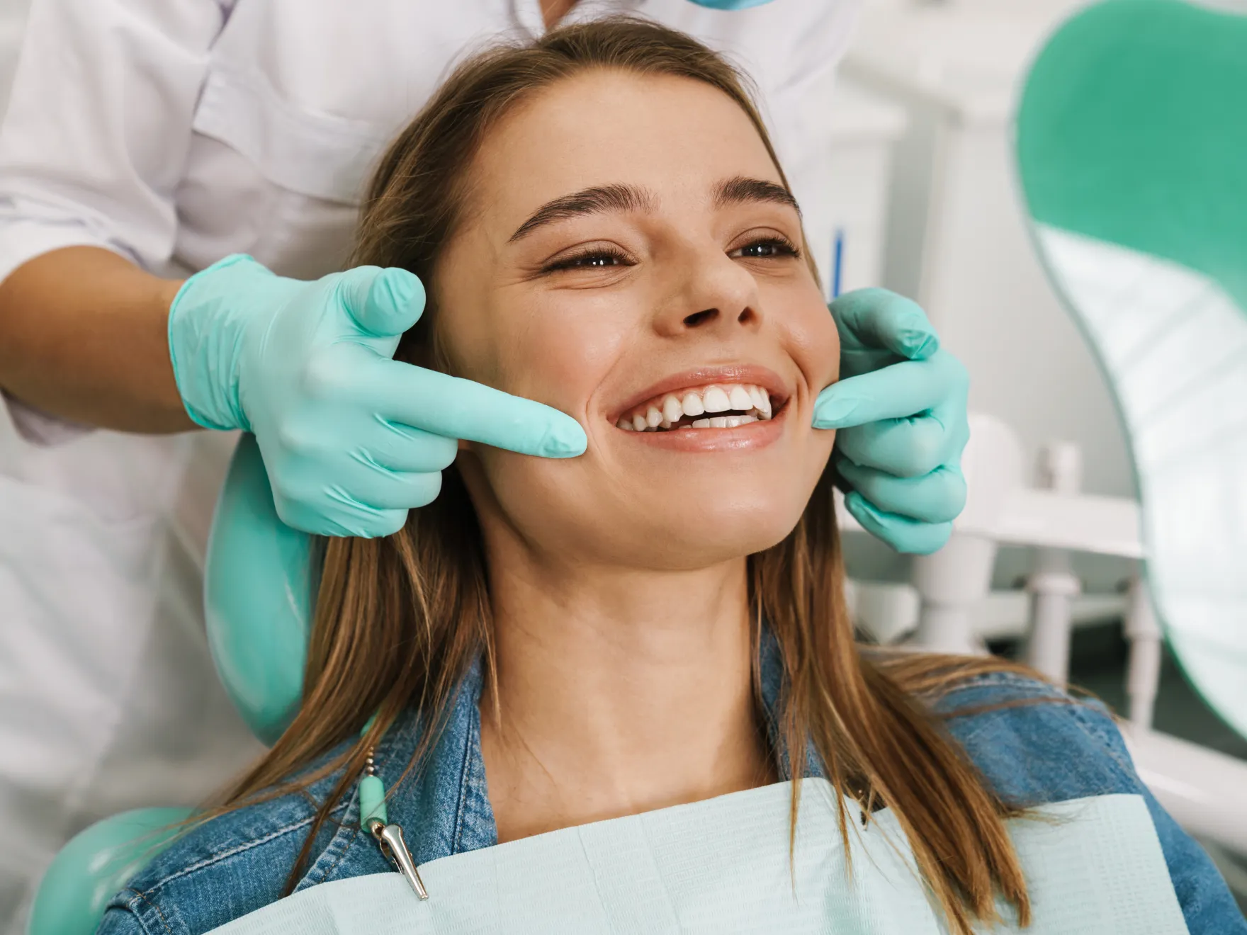 A dentist examines a smiling woman’s teeth during a dental check-up.