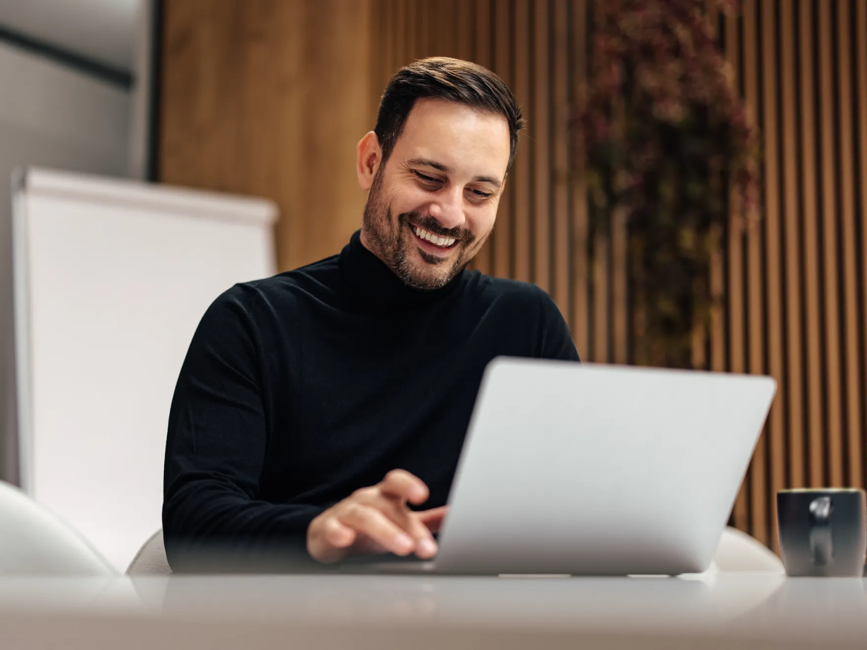 A man sitting at a table using a laptop computer.
