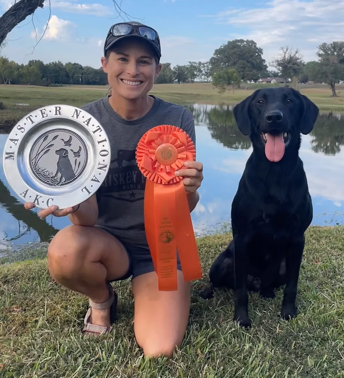 Success man holds a red ribbon while kneeling next to his dog