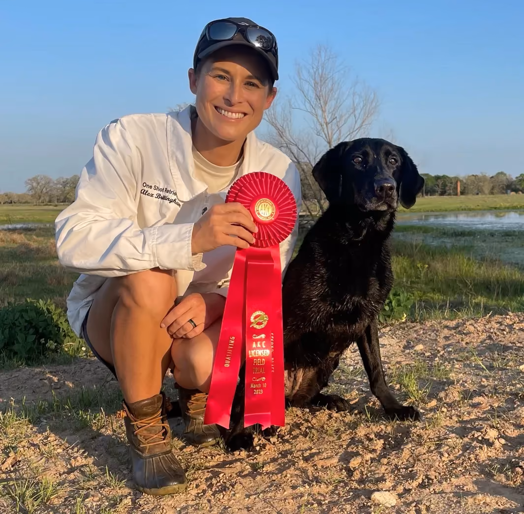 man holds a red ribbon and kneels next to his dog