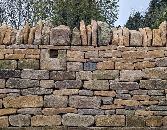 A mixed colour drystone wall with a unique stone feature included