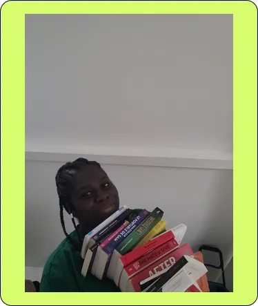 Founder of rovelia smiling and holding a large stack of colorful books indoors.