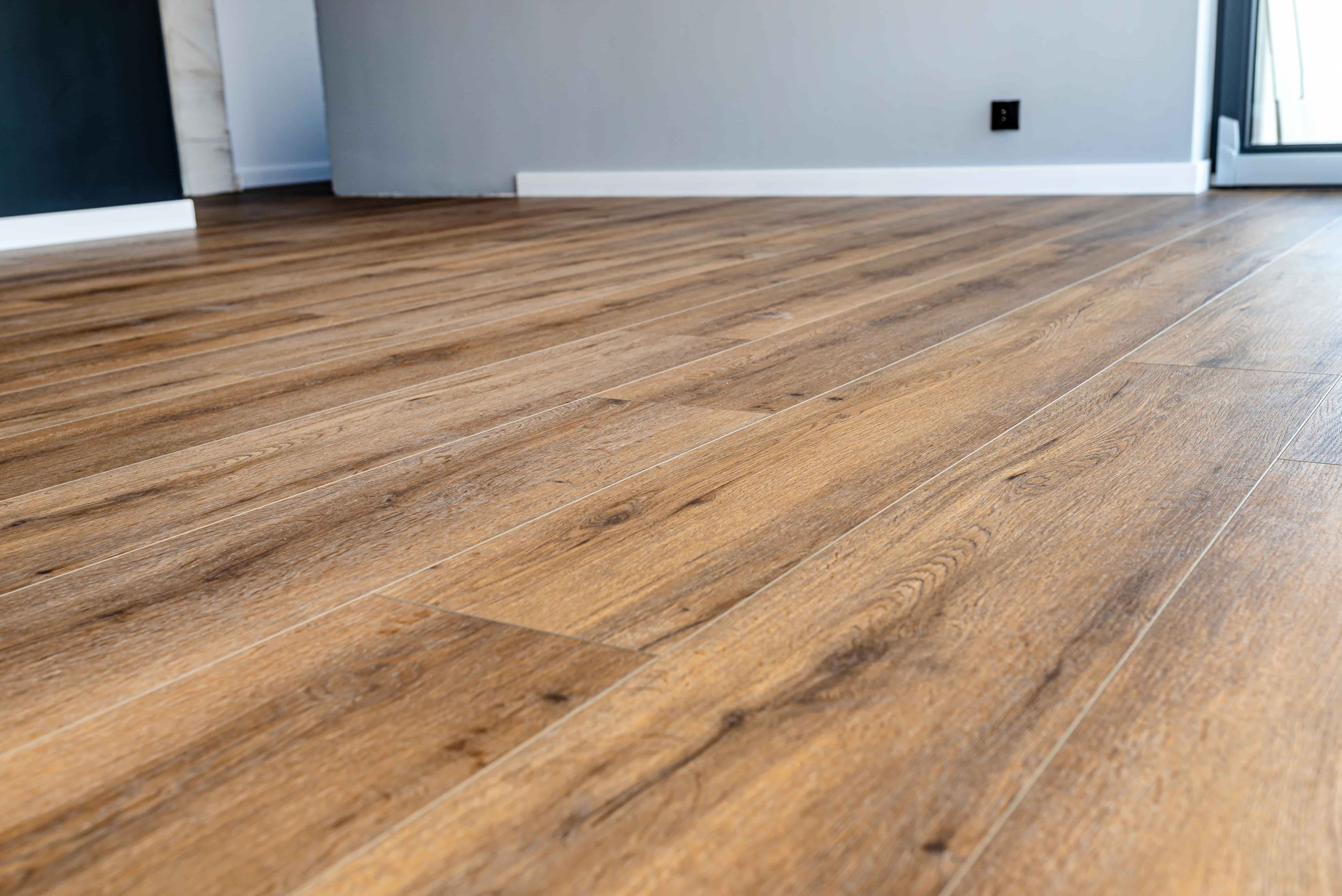 Living room floor with Vinyl Plank featuring a wood grain pattern. In the top of the picture a grey wall and a navy colored wall can be seen.