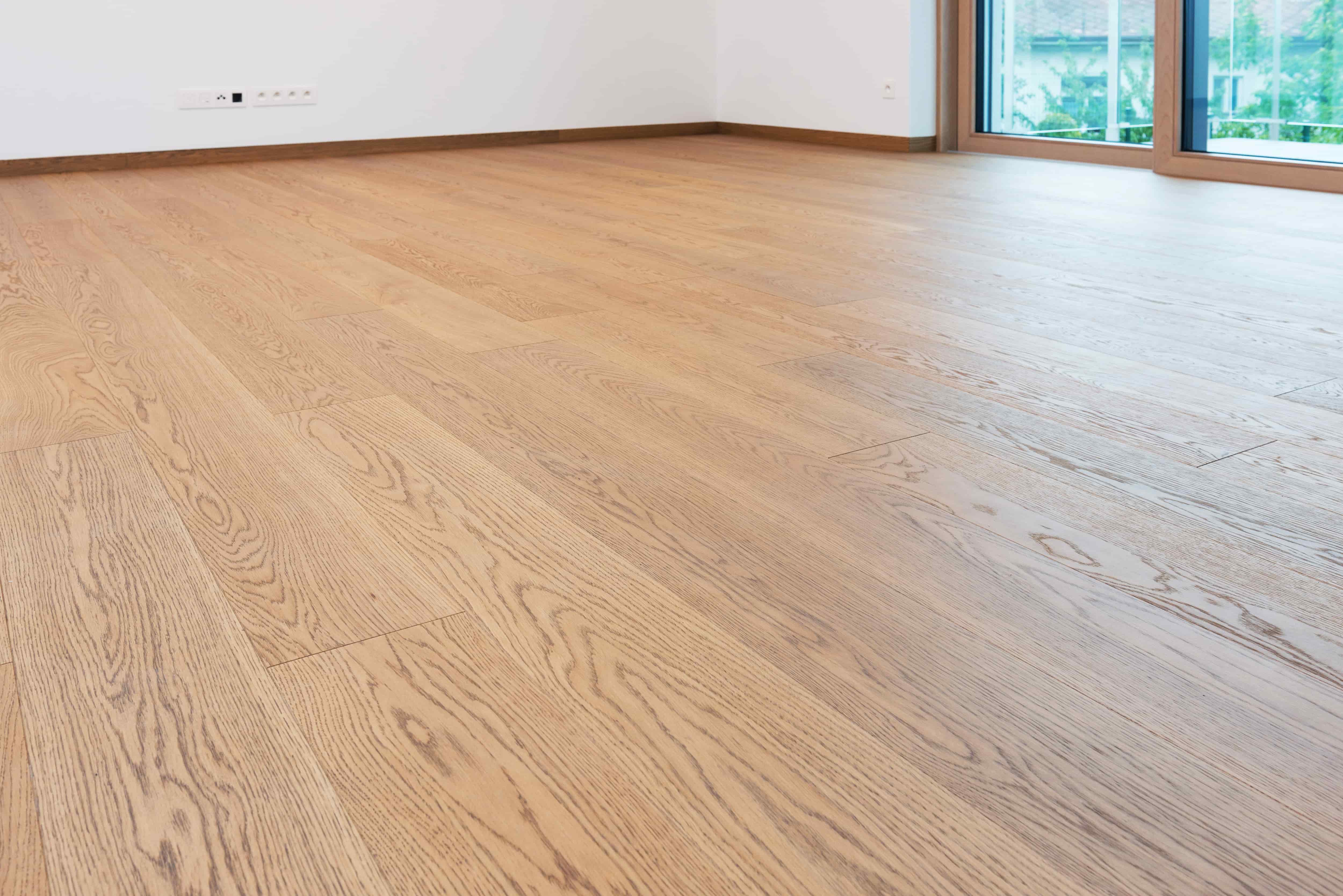 Light colored engineered hardwood with a wood grain pattern. A glass patio door is visible in the top right corner.