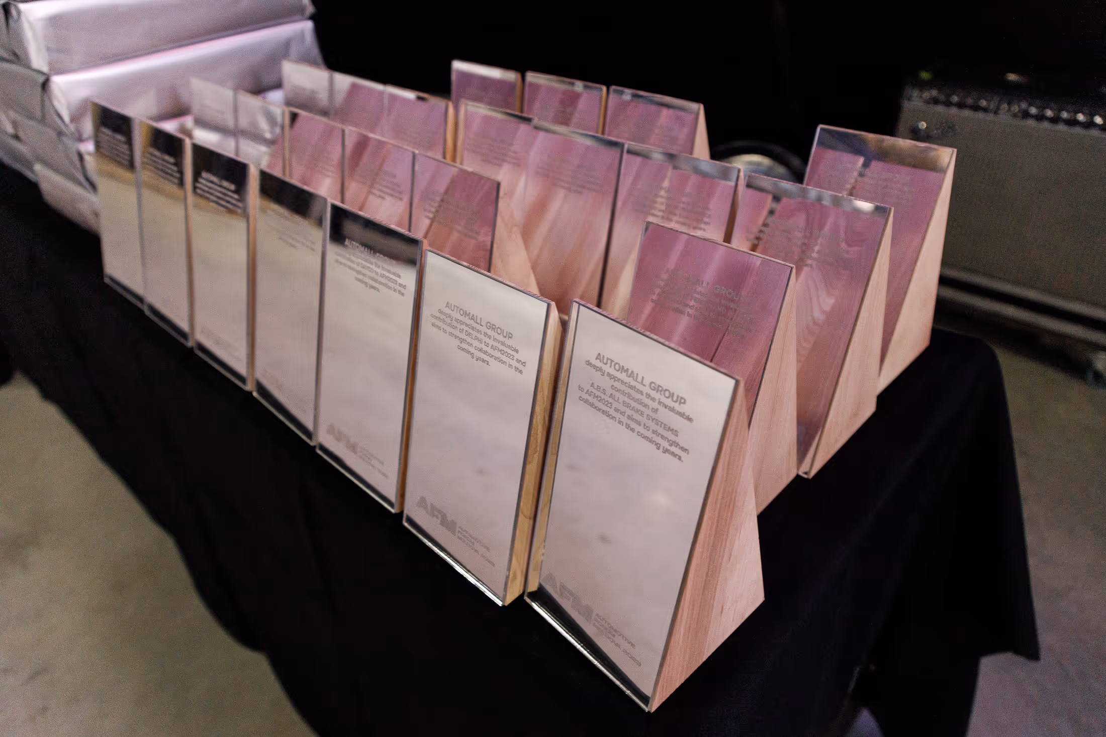 Ряд деревянных наград с металлическими табличками на черной скатерти.