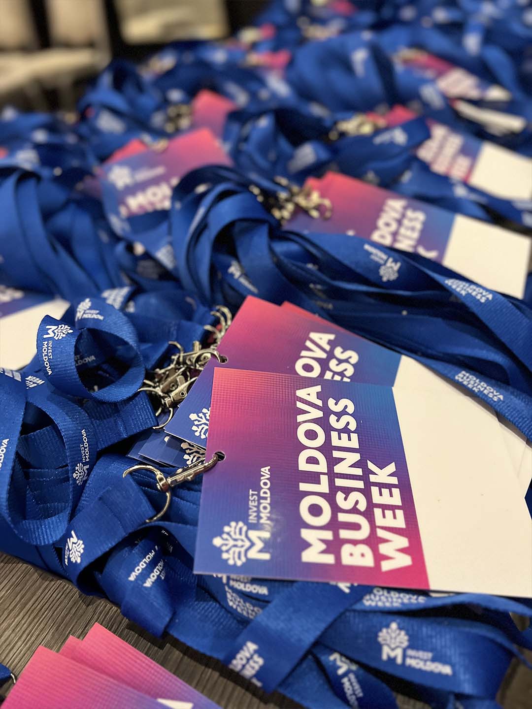 Бирюзовые бейджи с надписью Moldova Business Week на синей ленте Invest Moldova.