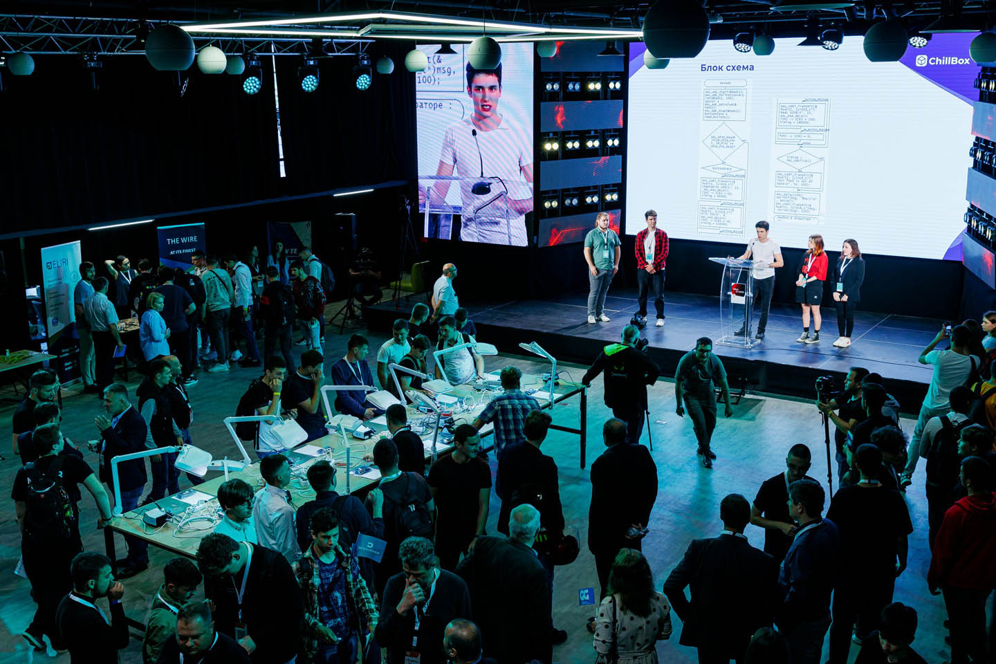 Большая группа людей на конференции, слушающих презентацию с блок-схемой на экране.