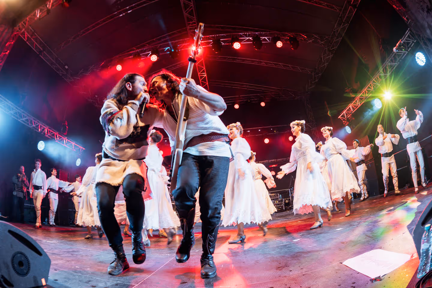 Музыкальный коллектив в традиционной одежде выступает на сцене с пением и танцами на фестивале.