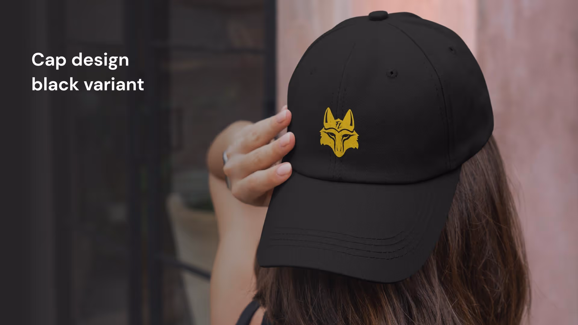 Черная кепка с вышитым желтым логотипом головы волка на передней панели, которую держит рука.