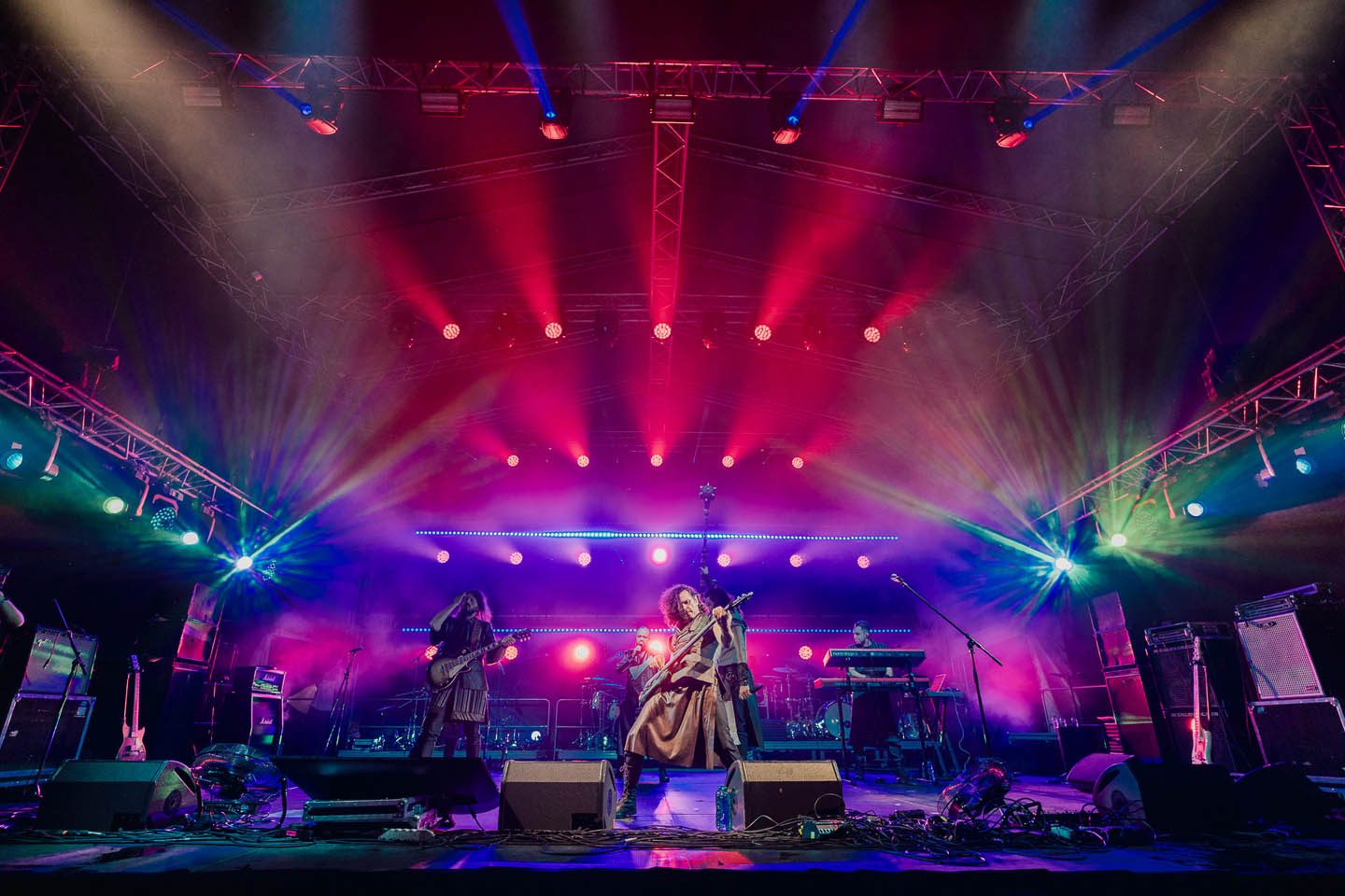 Выступление музыкальной группы на сцене с яркой разноцветной подсветкой и дымом.