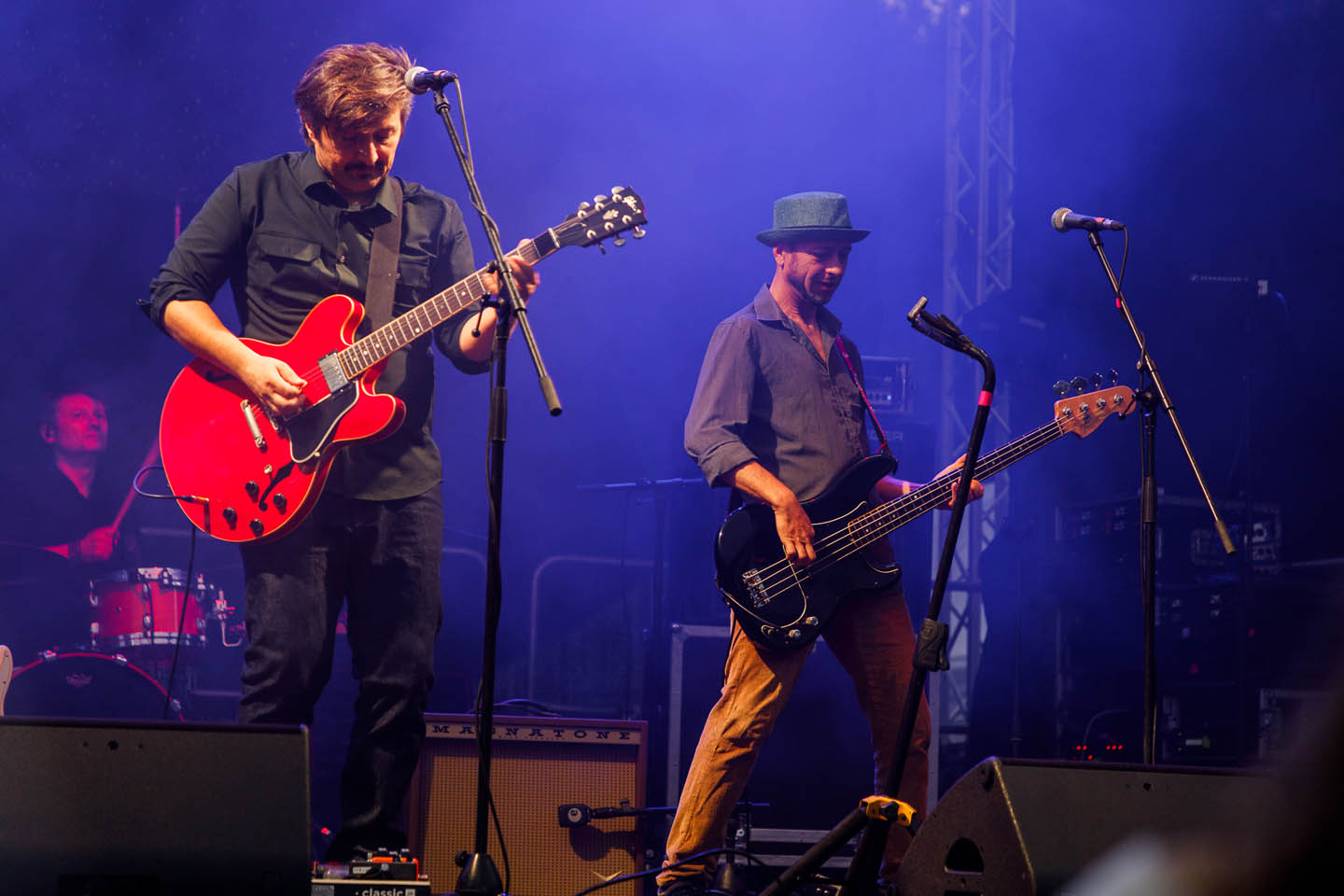 Музыкальная группа выступает на сцене с гитарой и бас-гитарой, исполнители сосредоточены на игре.