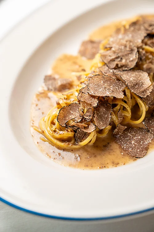 Burger with fried fries on black plate with sauce on the side