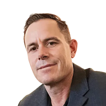 Portrait of a man with short brown hair wearing a dark blazer, looking at the camera with a slight smile.