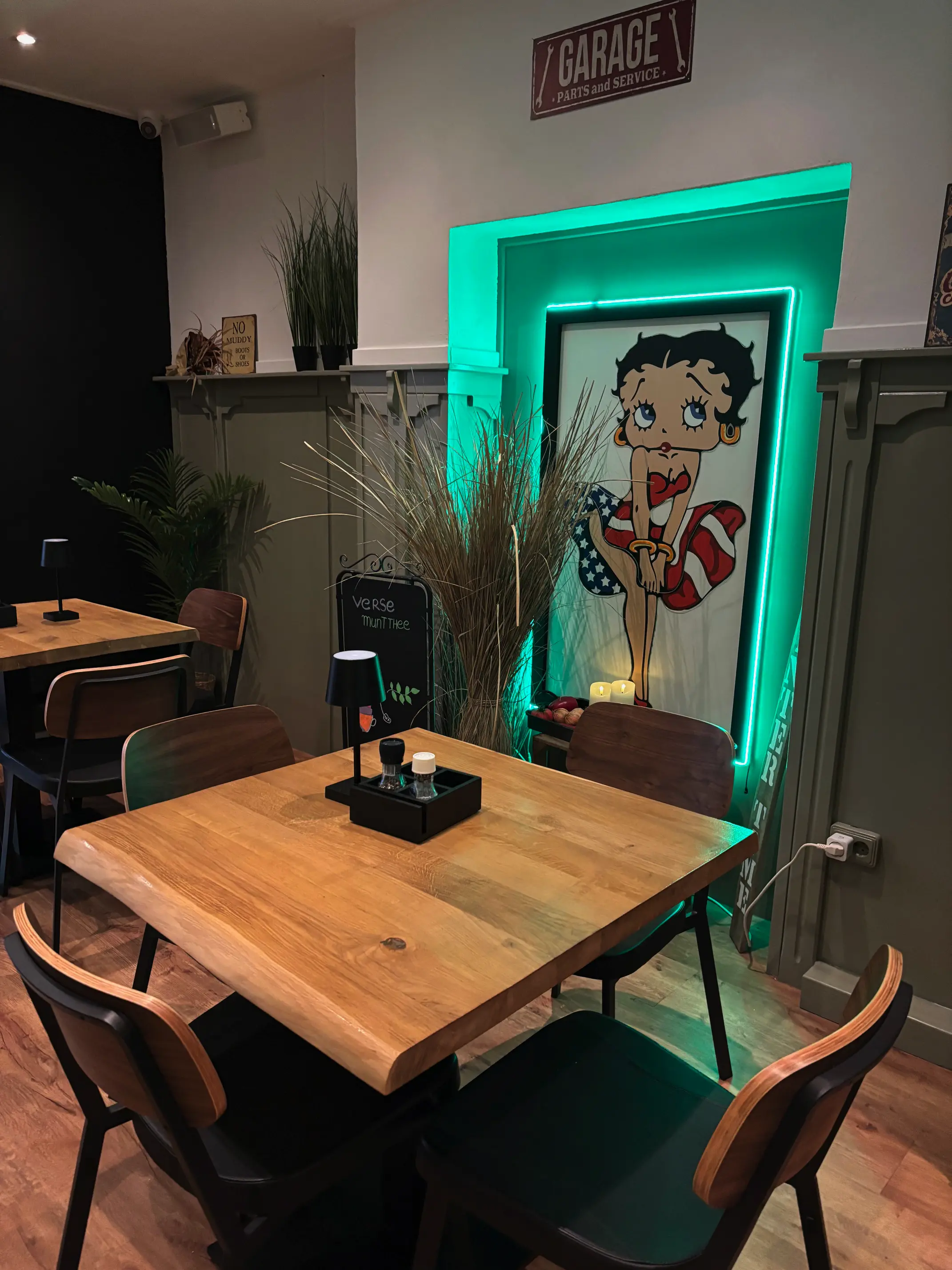 Binnenkant van de zaak van de kloes geleen. Je een tafel en een muurschilderij met neon lampen eromheen
