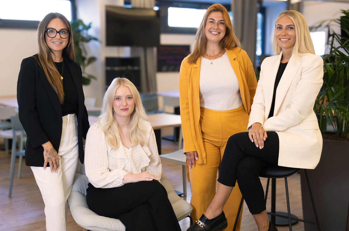 Teamfoto vom HR-Team bei bezahl.de, junge Frauen im modernen Business Look schauen frendlich in die Kamera