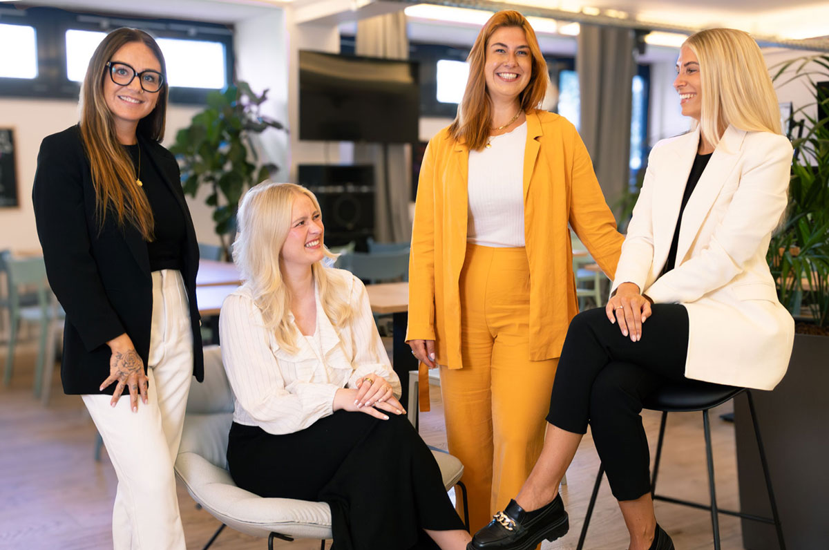 Teamfoto vom HR-Team bei bezahl.de, junge Frauen im modernen Business Look schauen frendlich in die Kamera, auf diesem Foto ist die Stimmung noch etwa ausgelassener.