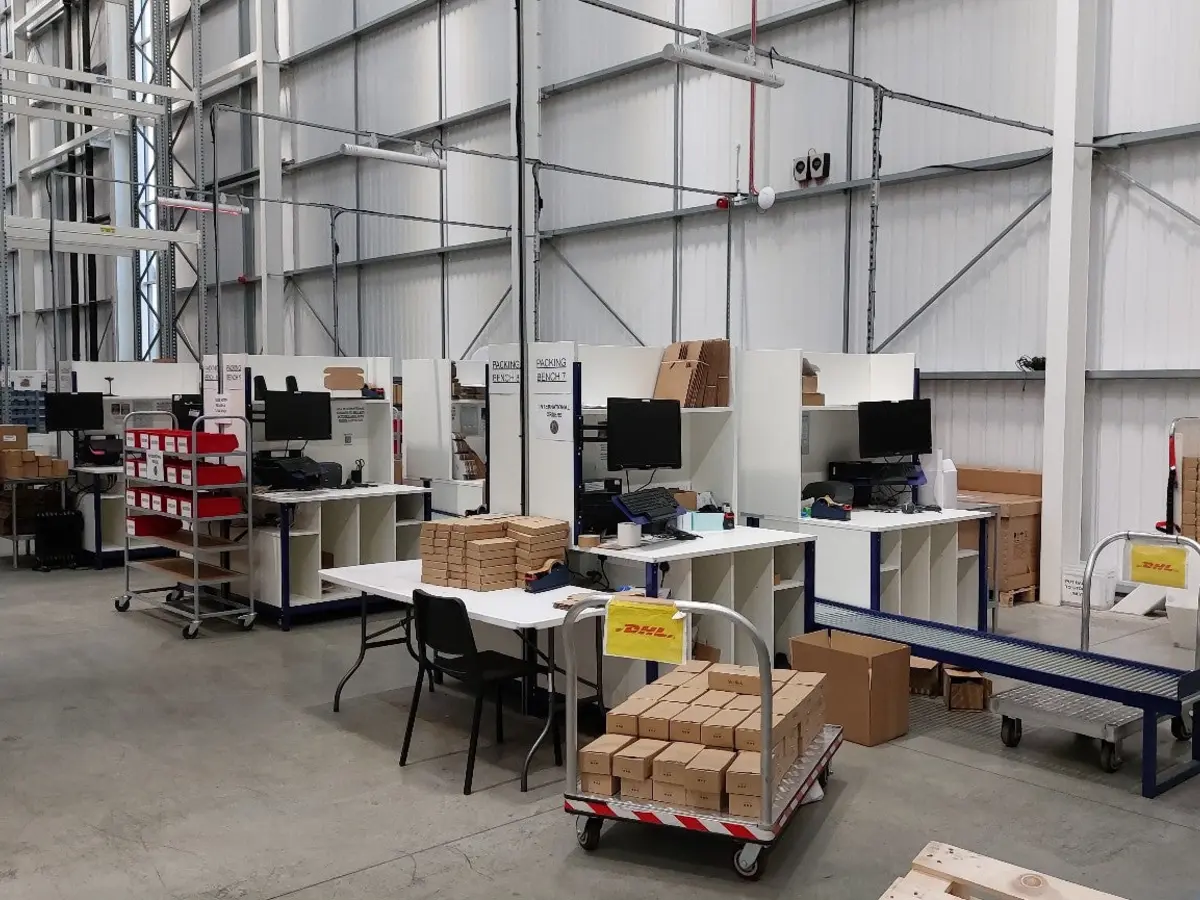 Warehouse packing area fitted with modular pack benches and conveyors