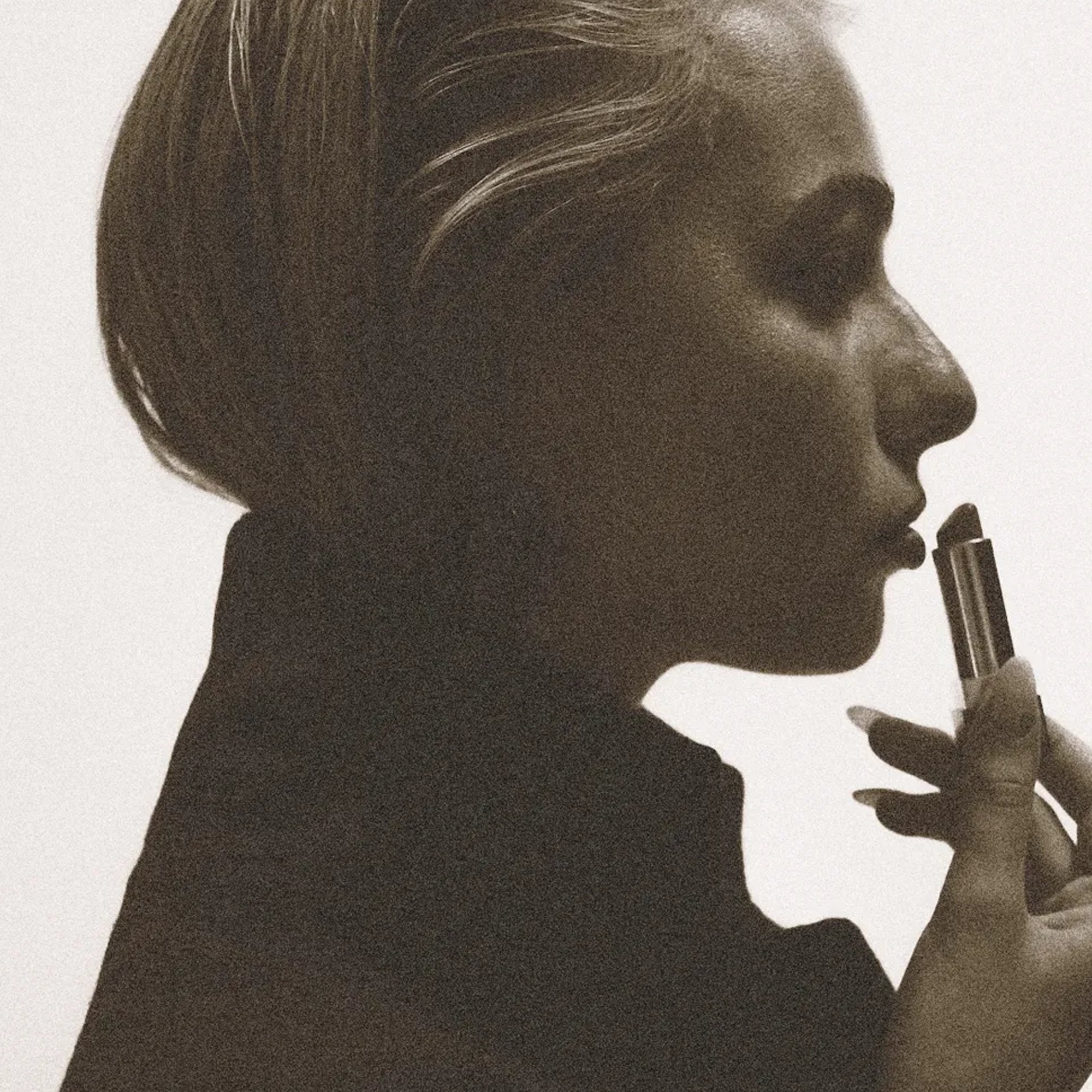 a women wearing a black wool coat by lutea studios, somerset with red lipstick applying her makeup.