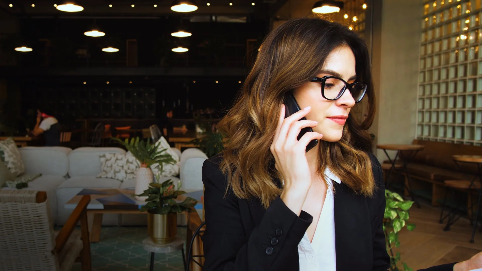 Woman on a phone call at a laptop in a softly lit office