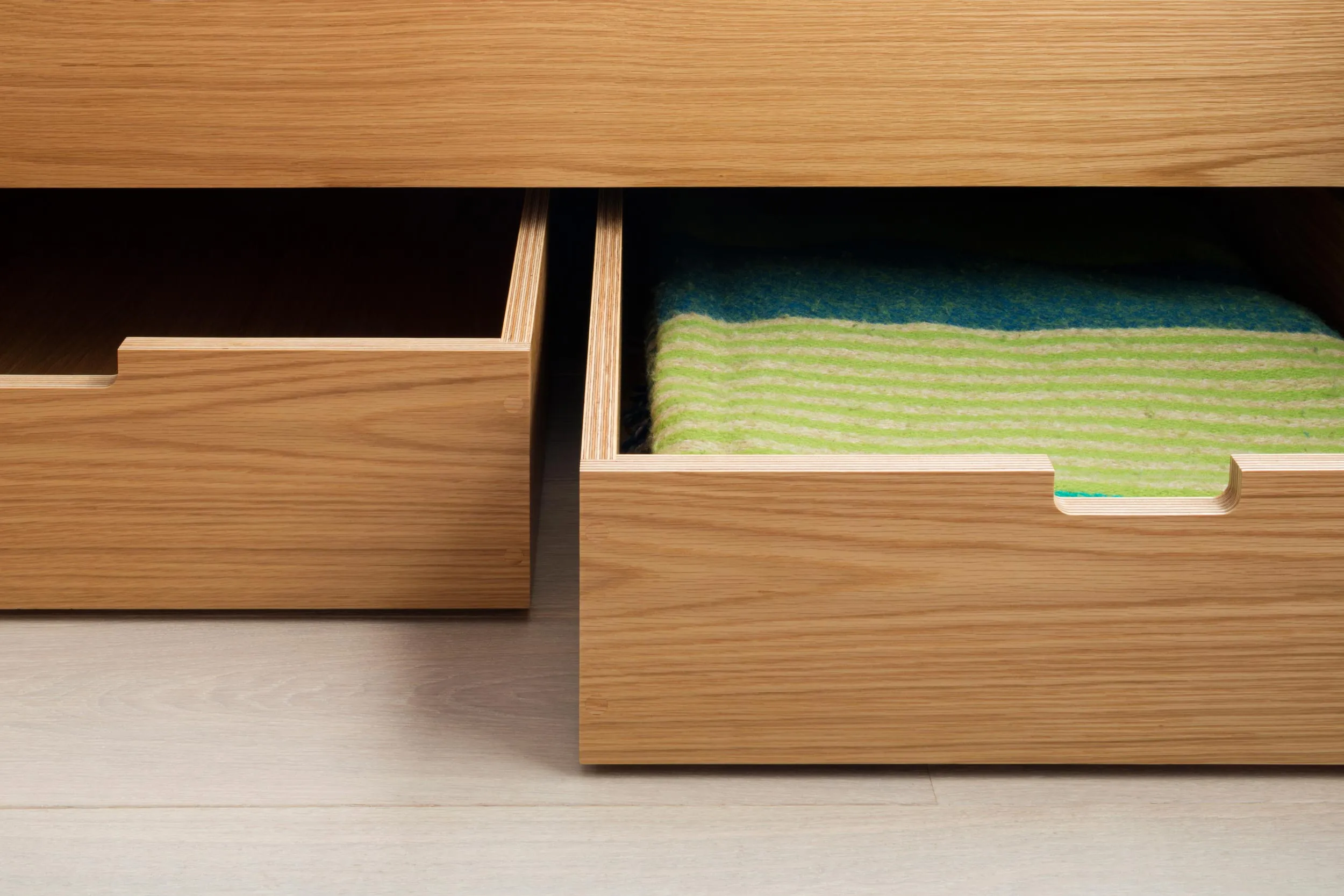 Oak-veneered plywood drawer with integrated handle detail and exposed birch ply edges by Uncommon Projects