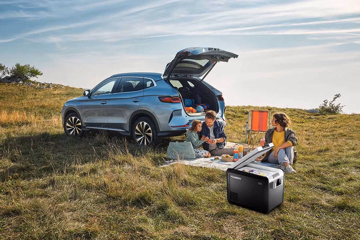 BYD steht am Feld und Familie macht ein Picknik.