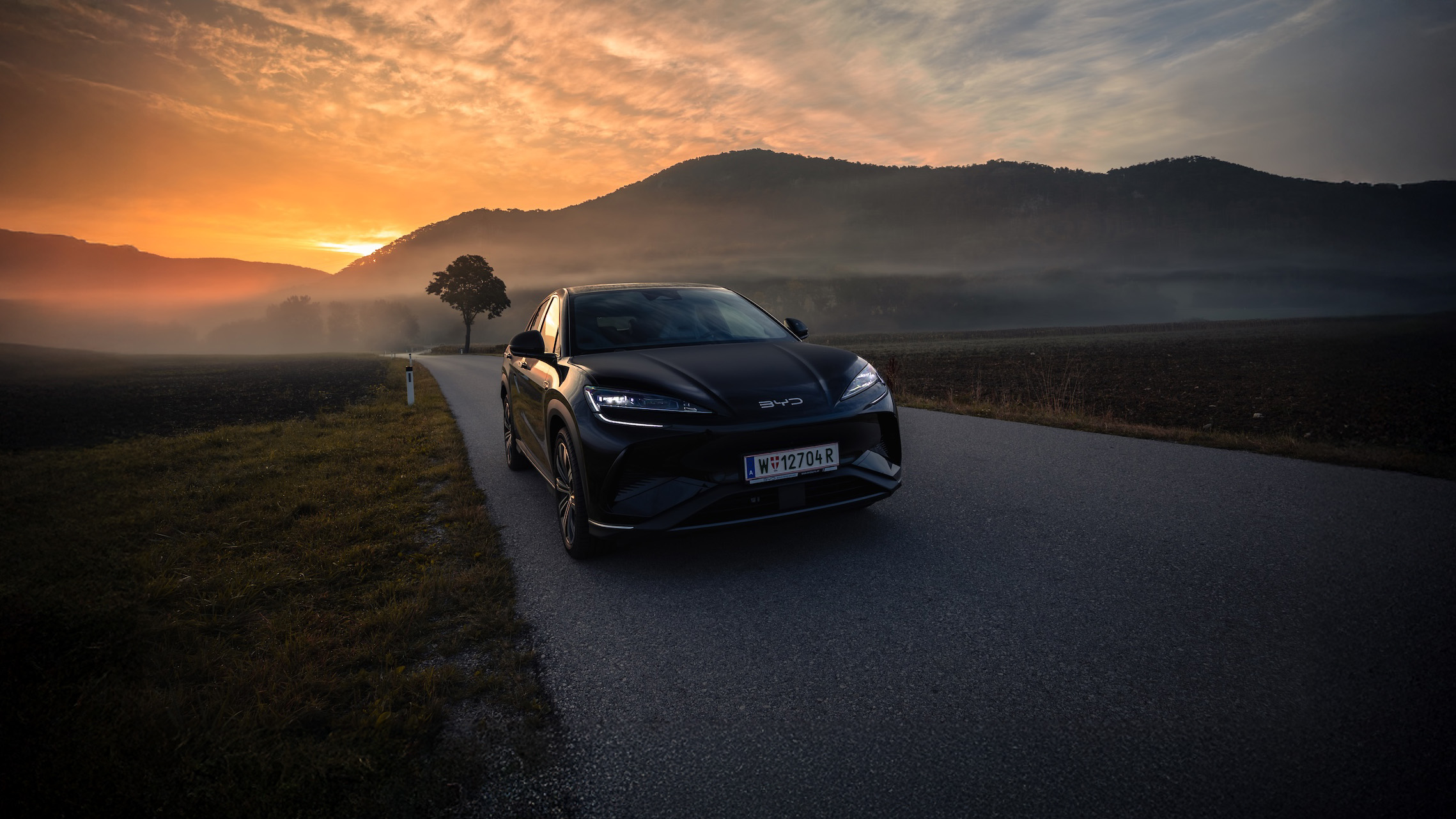 BYD SEAL U, Komplettansicht von Vorne, Dachbox, Fahrt auf Straße mit Meerblick