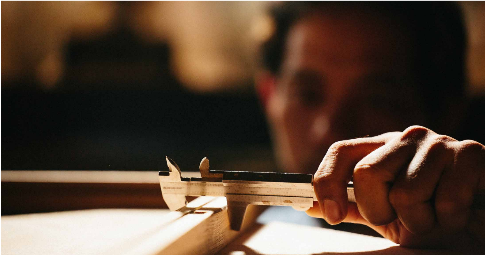 Craftsperson measuring a furniture component with calipers