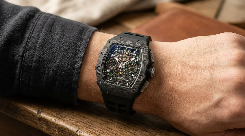 Luxe Richard Mille sporthorloge met een zwarte rubberen band liggend op een donkere ondergrond