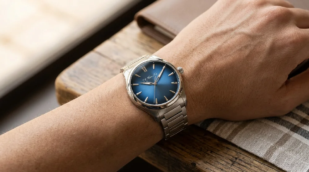 Luxe H. Moser & Cie horloge met een blauwe wijzerplaat plat liggend op een donkere ondergrond