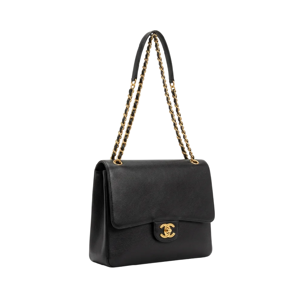 Close-up van een luxe zwarte Chanel 22 tas, met de iconische gewatteerde look en kettinghengsels, liggend op een lichte ondergrond.
