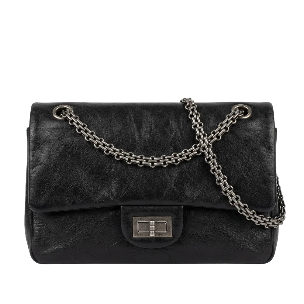 Chanel 2.55 Reissue tas in zwart leer met zilverkleurige hardware op een lichtgrijze achtergrond