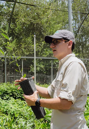 A man holding a potted plant in a garden.