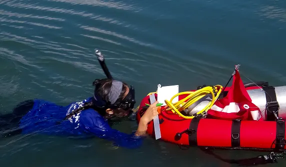 A person in a body of water with a life jacket on.