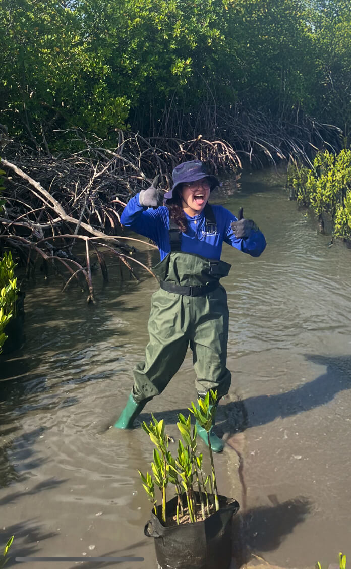 A man in a blue shirt and green pants jumping into a river.