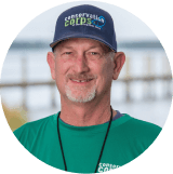 A man wearing a hat and a green shirt.