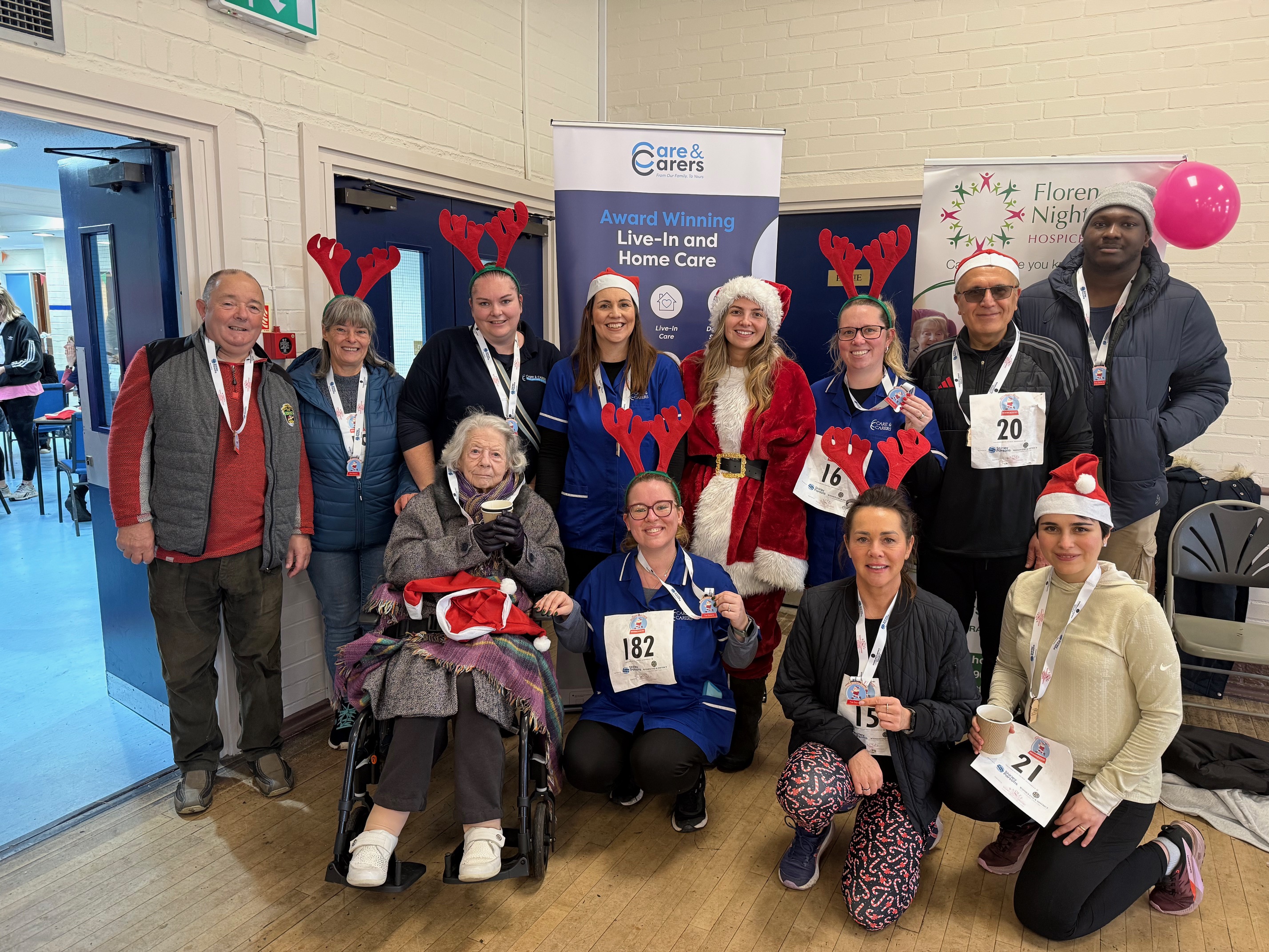 Group photo of Care & Carers staff and clients wearing festive outfits and medals after participating in the Haddenham Santa Dash event.