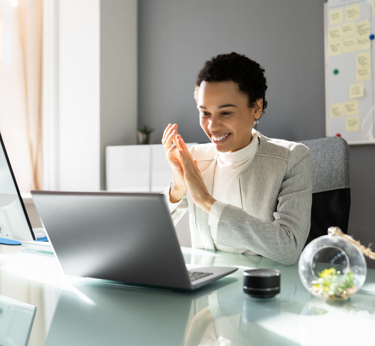 a woman clapping in celebration while looking at her computer screen