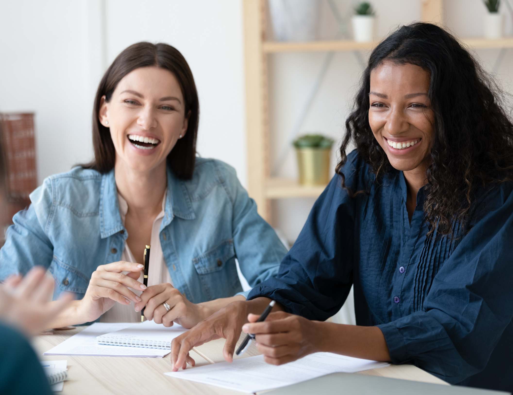 Two coworkers share a laugh while working on a project together. Featured in "10 quotes about employee engagement."