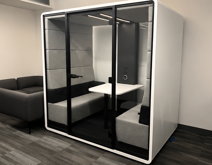 Black-and-grey acoustic meeting pod with bench seating in a Toronto office