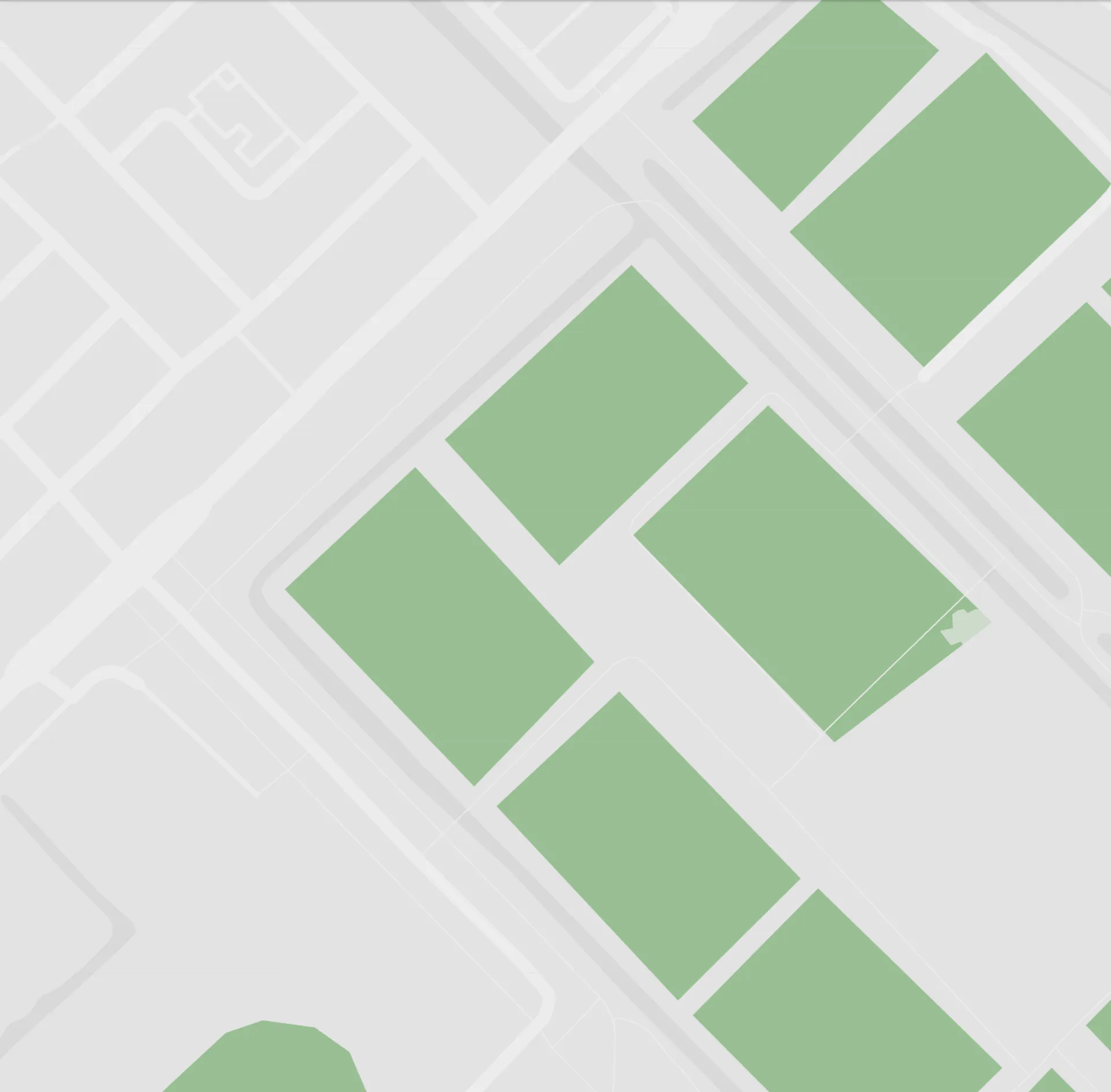 Simplified map with green rectangular areas representing parks or buildings, surrounded by light gray streets.