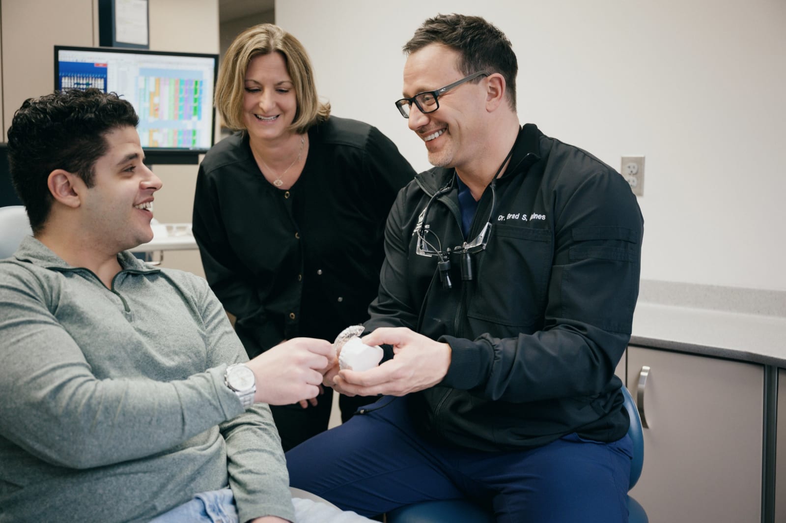 Male dentist and female assistant consulting with male patient in office