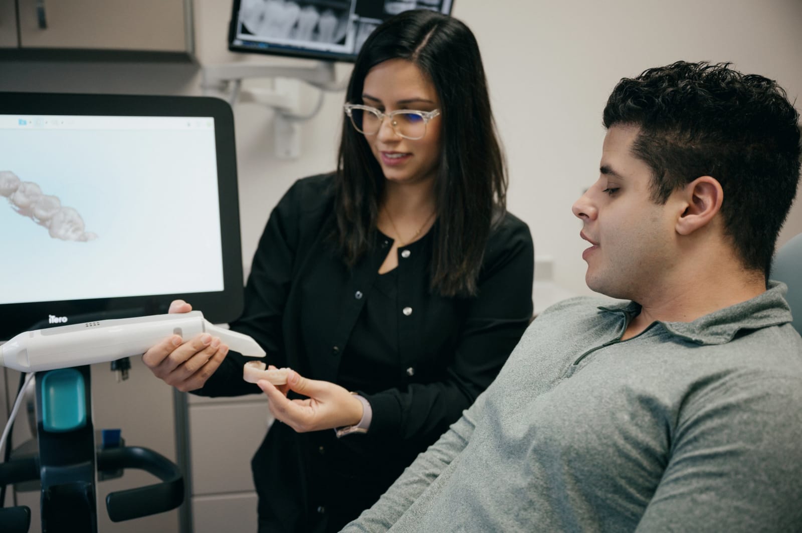 Female dentist discussing treatment plan with male patient in exam room