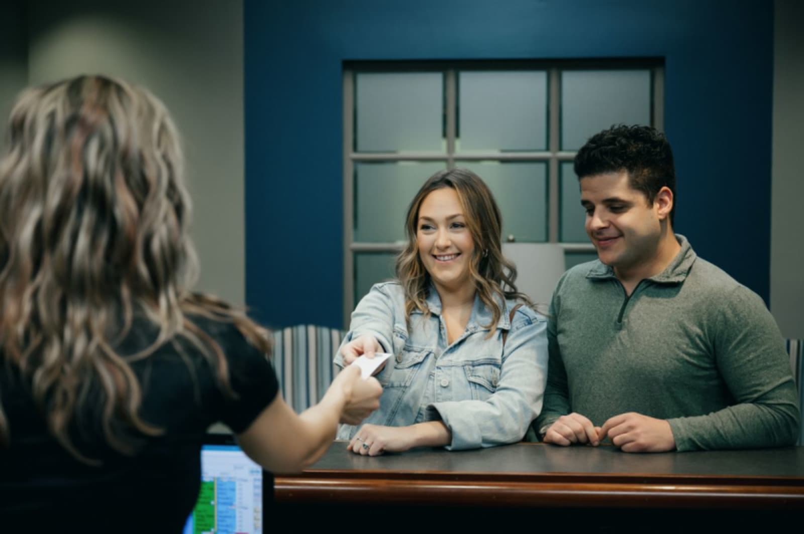 Dental team member discussing treatment options with female patient at office consultation desk.