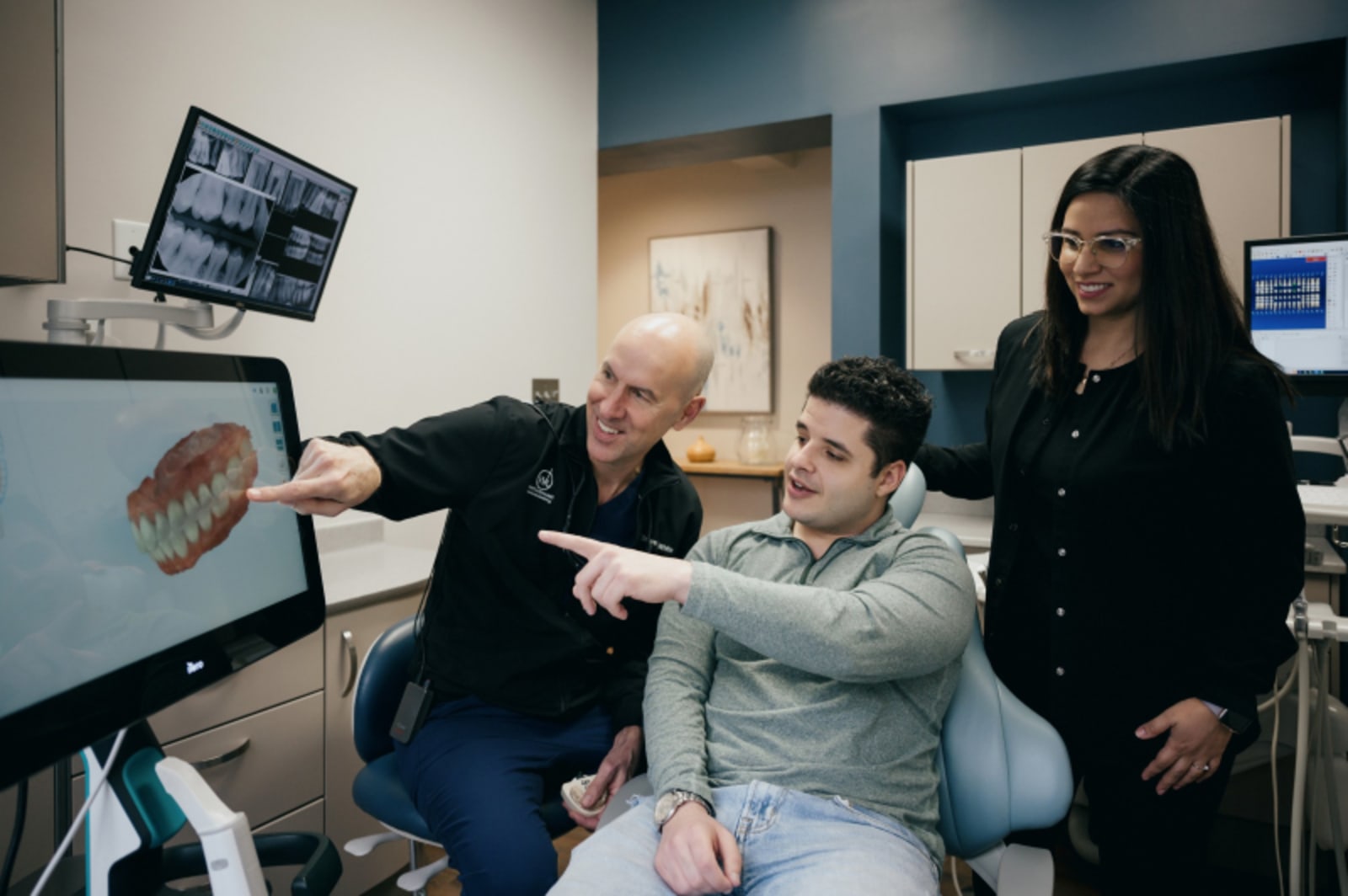 Dentist discussing oral health concerns with patient in modern dental office treatment room.