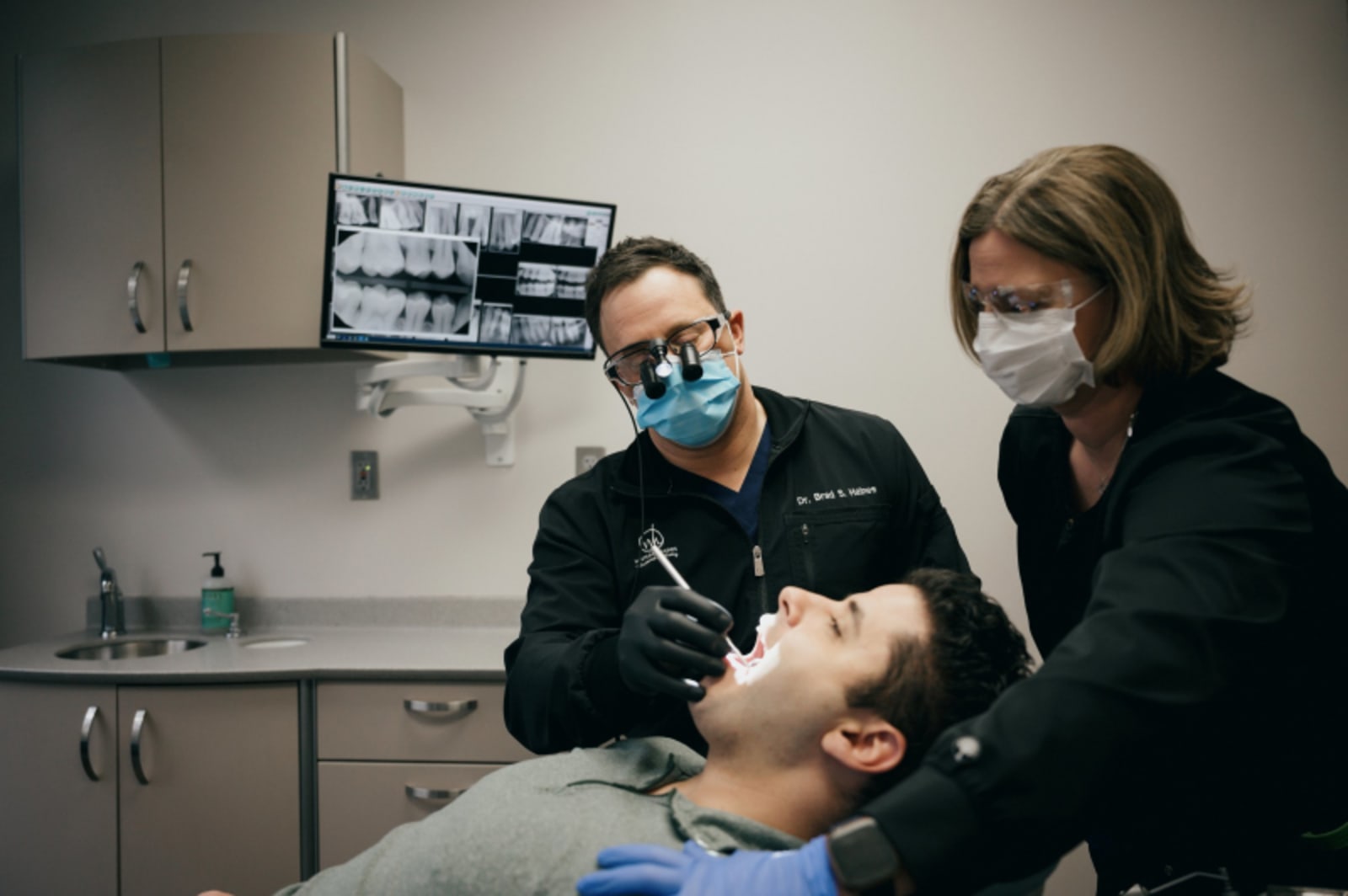 Dentist pointing to X-rays while explaining treatment to a patient in the operatory