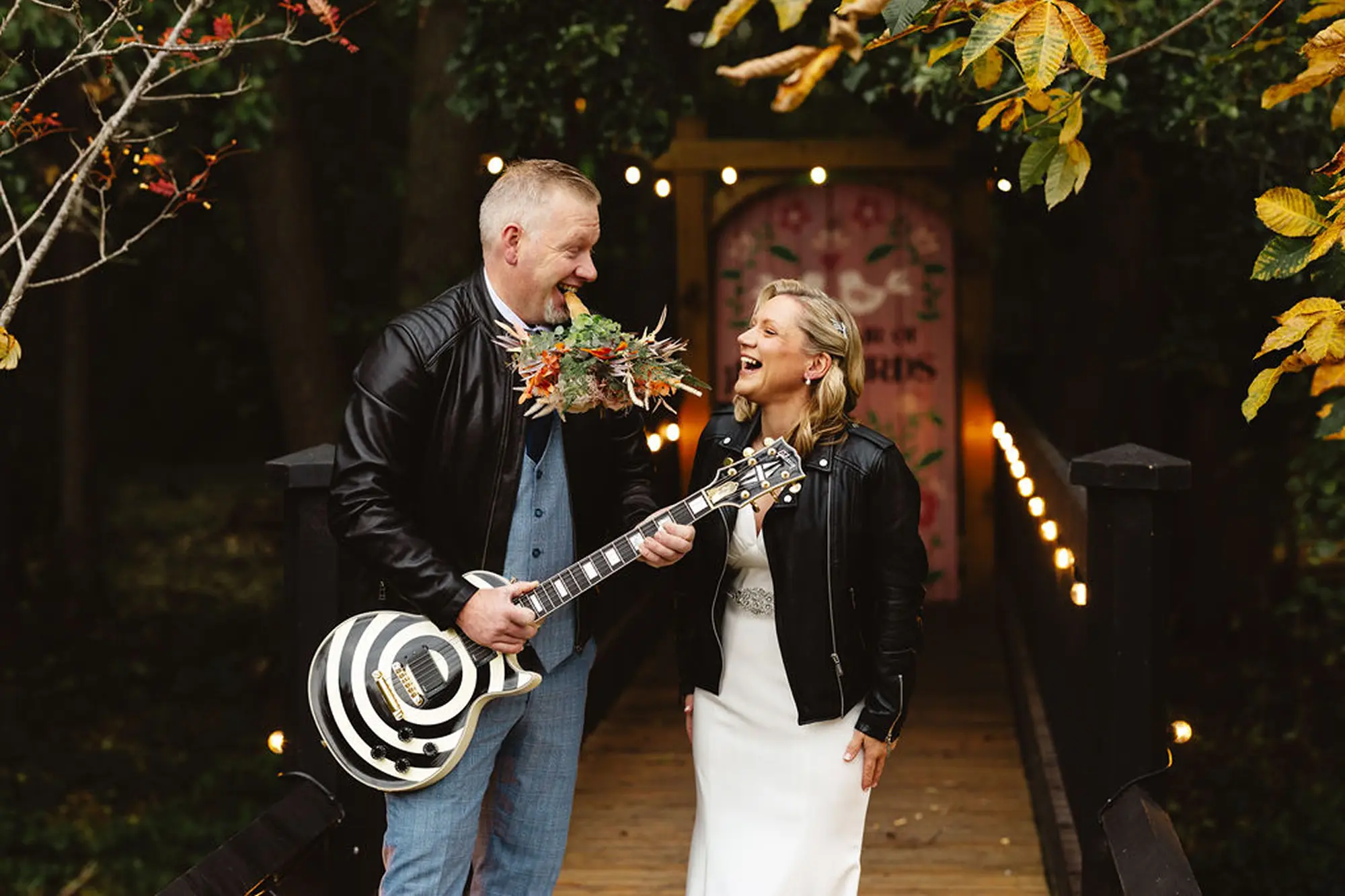 Couple in leather jackets with a guitar on the woodland bridge at Blackbrook Barns, Lichfield, Staffordshire