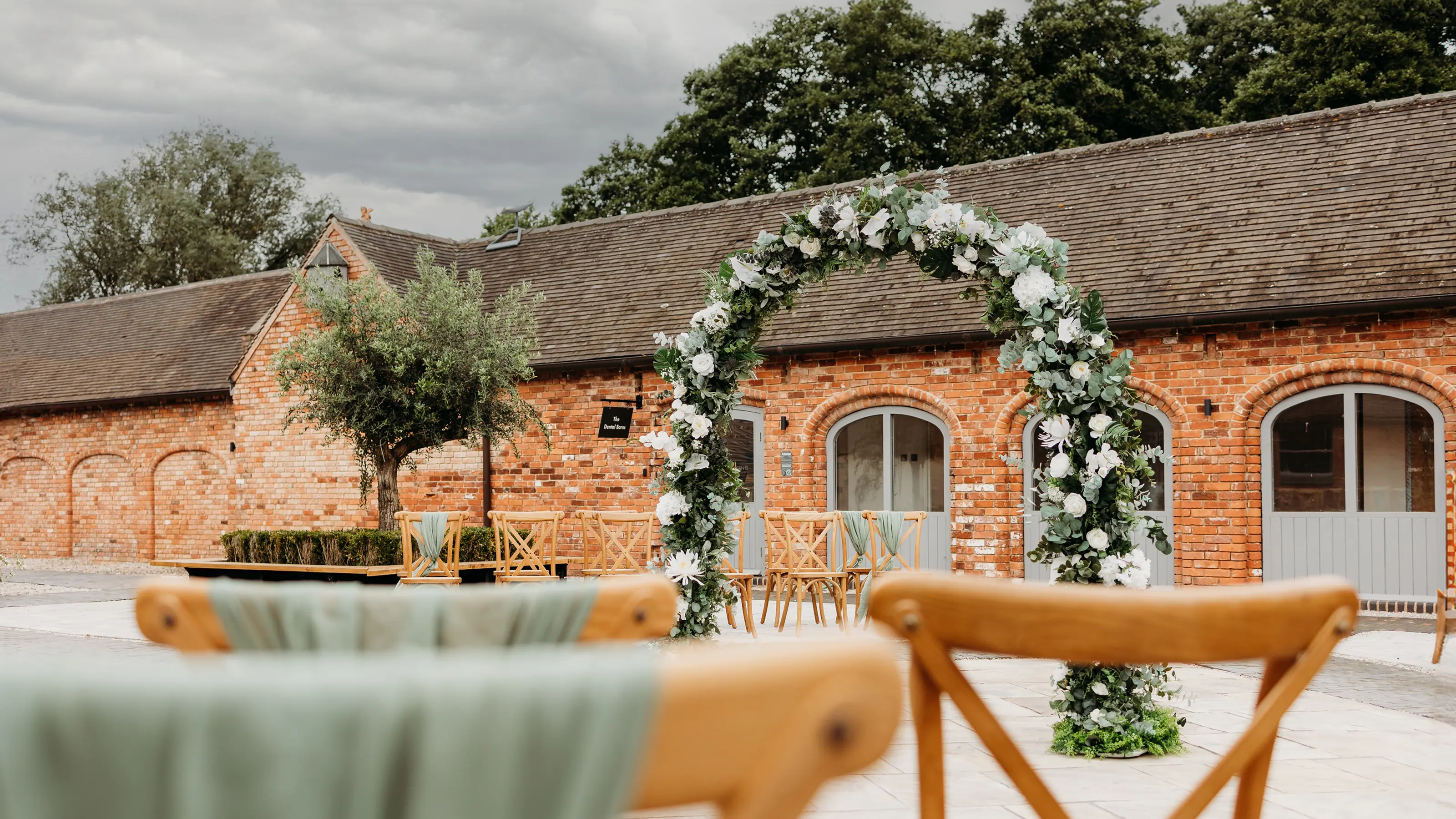 The Lower Courtyard set for an outdoor ceremony with a floral arch at Blackbrook Barns, Lichfield, Staffordshire