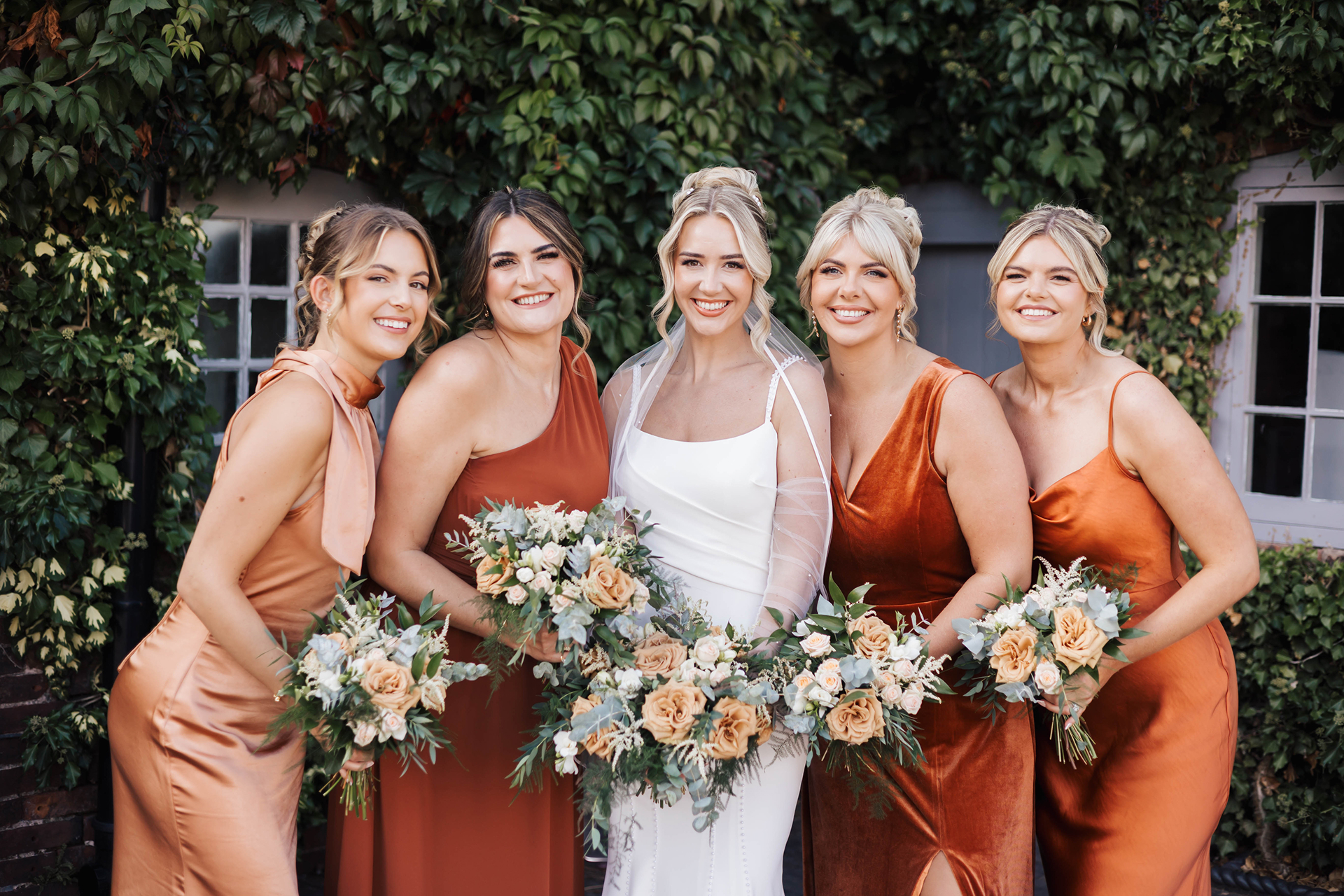 Bride with bridesmaids in rust dresses holding bouquets at Blackbrook Barns, Lichfield, Staffordshire